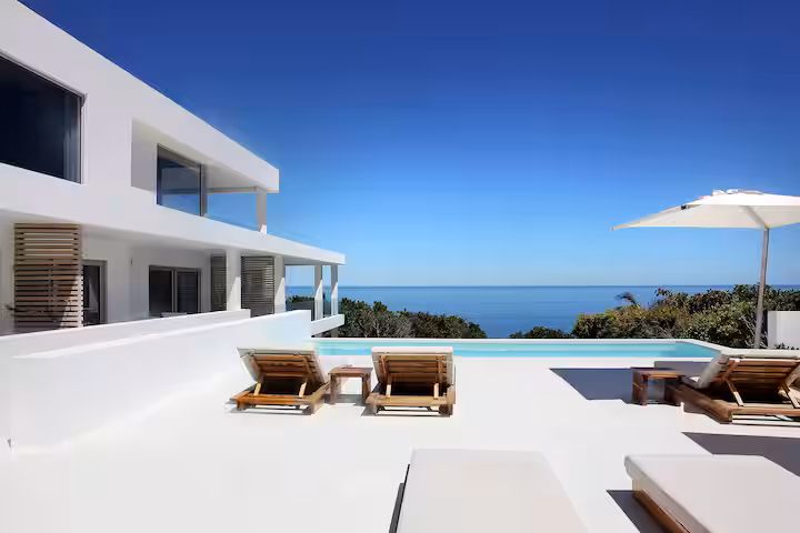 The pool and sun deck along the side of the house, loungers out, the Atlantic beyond